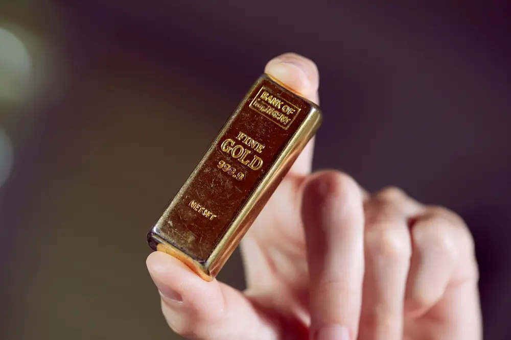 Small 1 gram gold bar held between fingers
